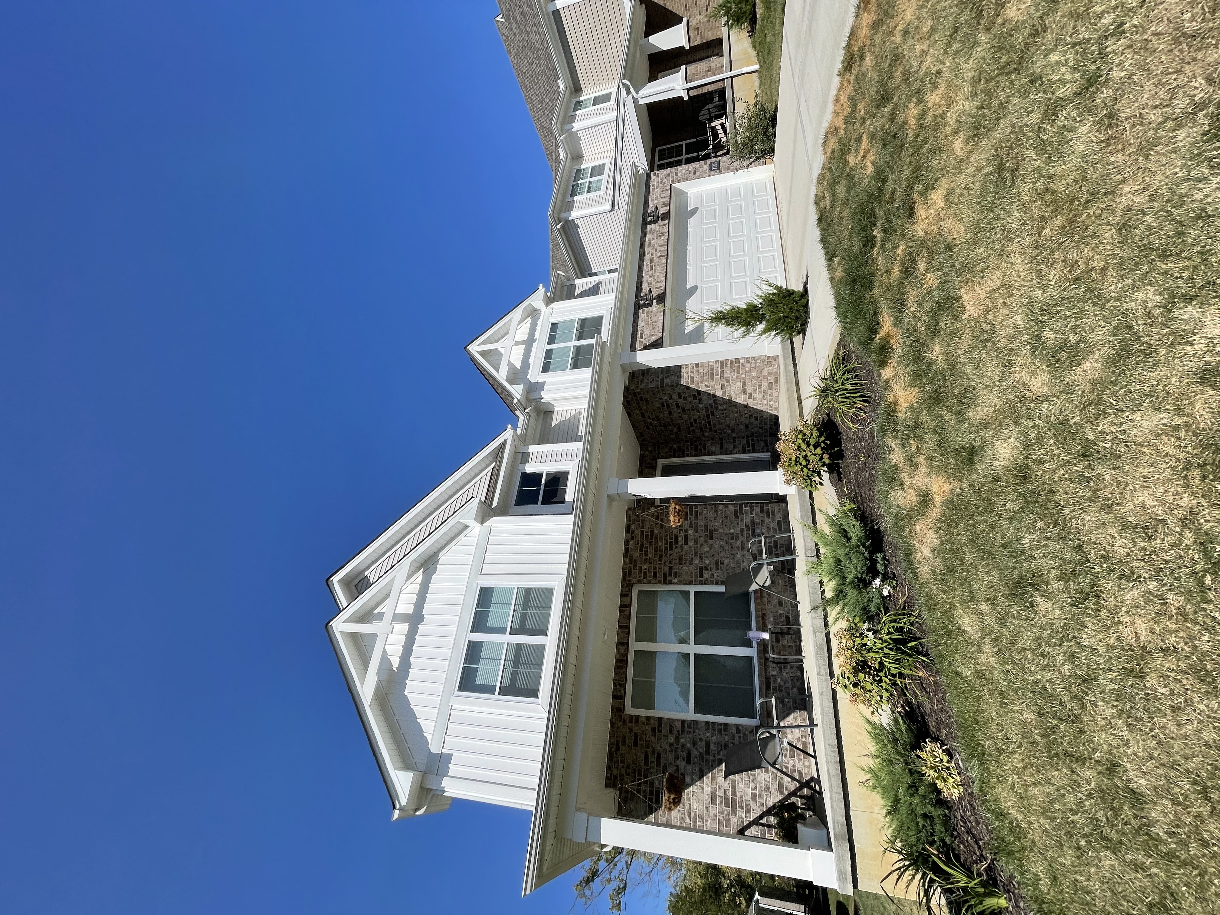 Low-pressure soft washing cleaning a white farmhouse exterior in St. Petersburg, FL — Caldwell Clean